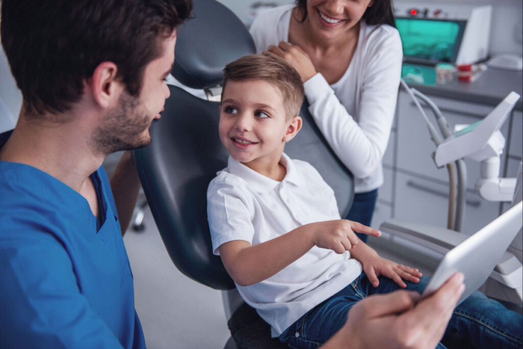 Child in dental chair in conversation with dentist